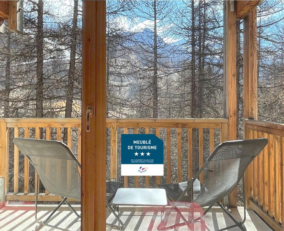 une terrasse couverte avec 2 chaises et un panneau. dans l'établissement CosyRefuges - Le Refuge des Marmottes, à Vars
