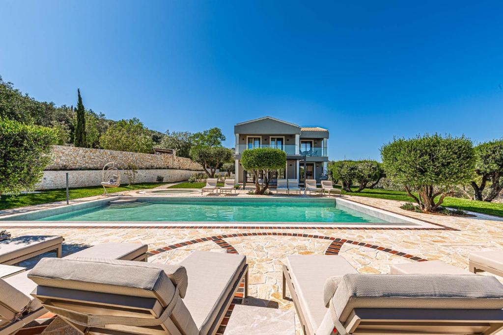 a swimming pool with chairs and a house at Villa Arthur in Kassiopi
