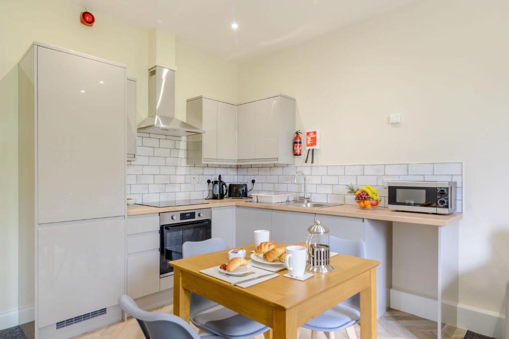 una piccola cucina con tavolo e sedie in legno di Cote Ghyll Mill Holiday Apartments a Osmotherley
