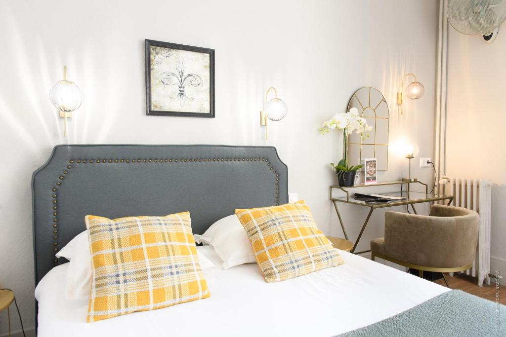 - une chambre avec un lit doté d'oreillers jaunes et blancs dans l'établissement A l'Hôtel Des Roys, à Versailles