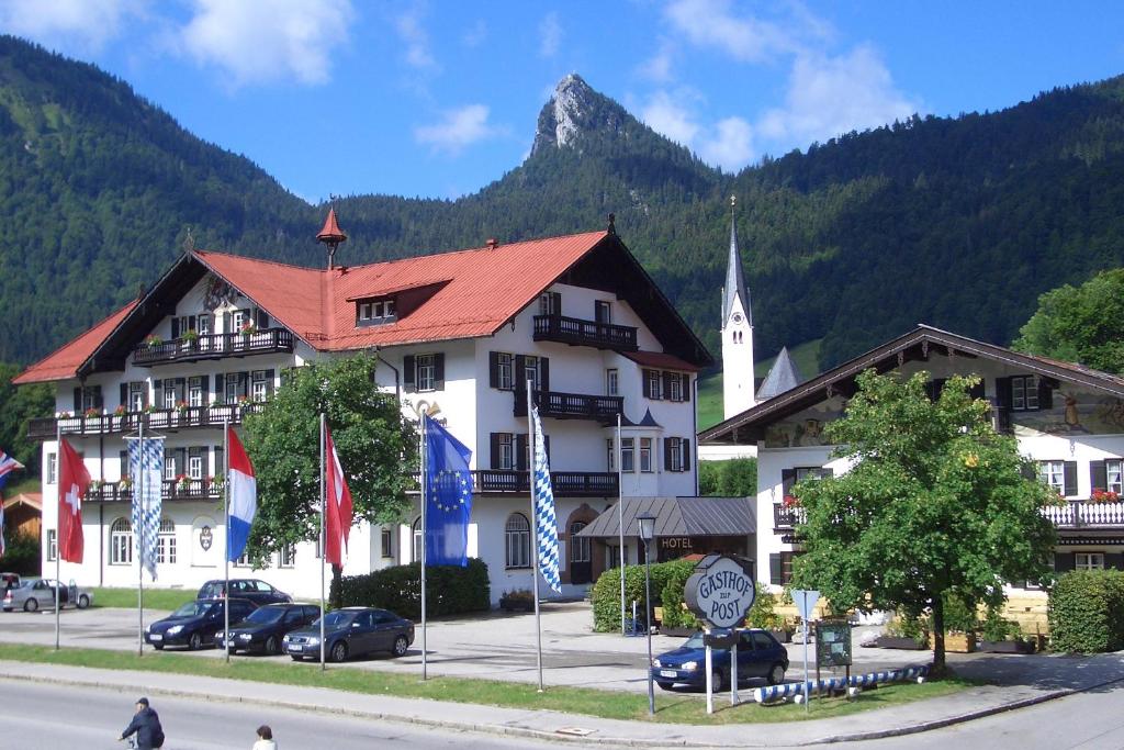 un grand bâtiment blanc avec une église dans les montagnes dans l'établissement Hotel zur Post, à Kreuth