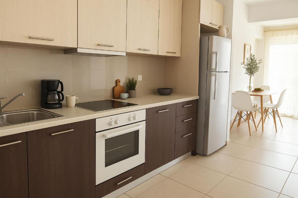 La cuisine est équipée de placards bruns et d'un réfrigérateur blanc. dans l'établissement ''SEA AND SKY'', à Agios Nikolaos