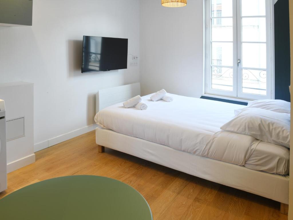 une chambre avec un lit et une télévision au mur dans l'établissement Le Cocon studio, cognac, à Cognac