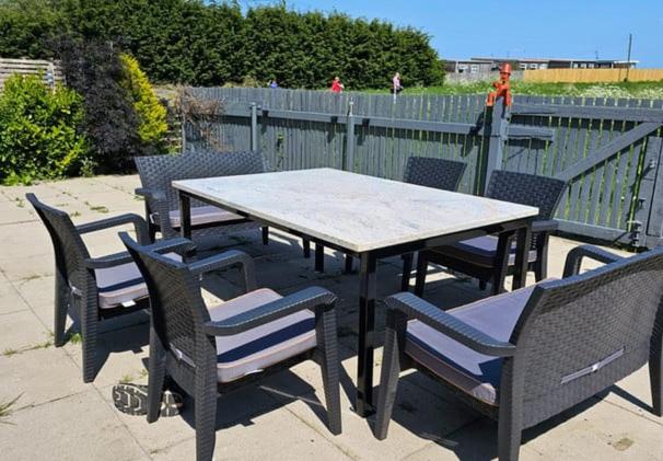 ein Picknicktisch mit Stühlen und ein Tisch und ein Zaun in der Unterkunft Primrose Valley Bungalow in Filey