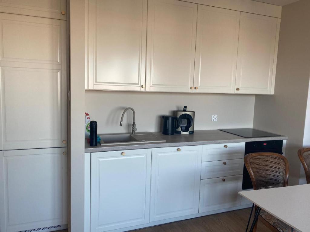 a kitchen with white cabinets and a sink at Przytulne mieszkanie na krótki pobyt, spacerem na starówkę in Toruń