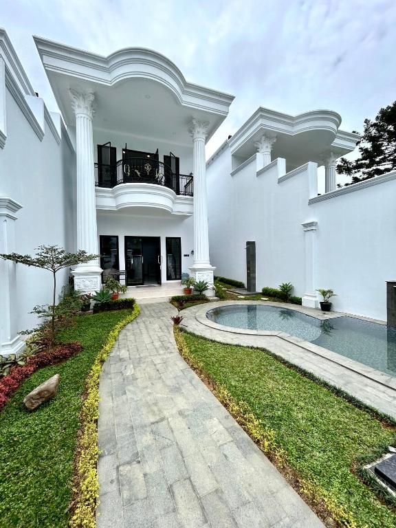 a large white house with a swimming pool and columns at Classic Resort Puncak in Campaka