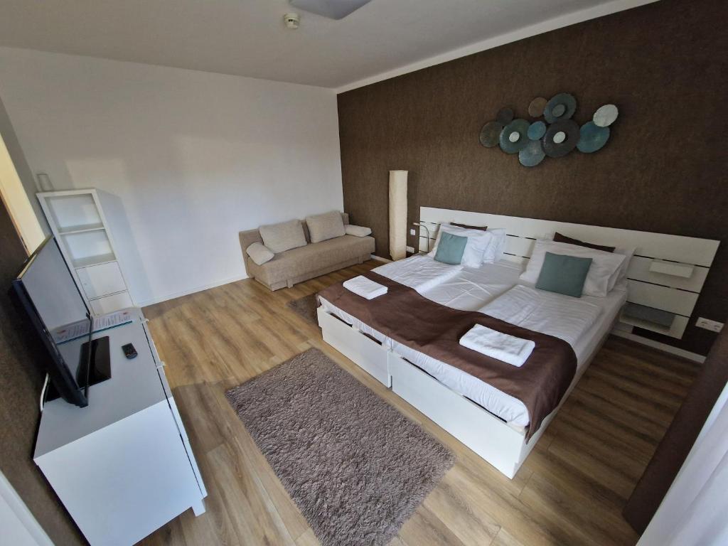 a bedroom with a large bed and a couch at Apartment Sunrise in Zalakaros