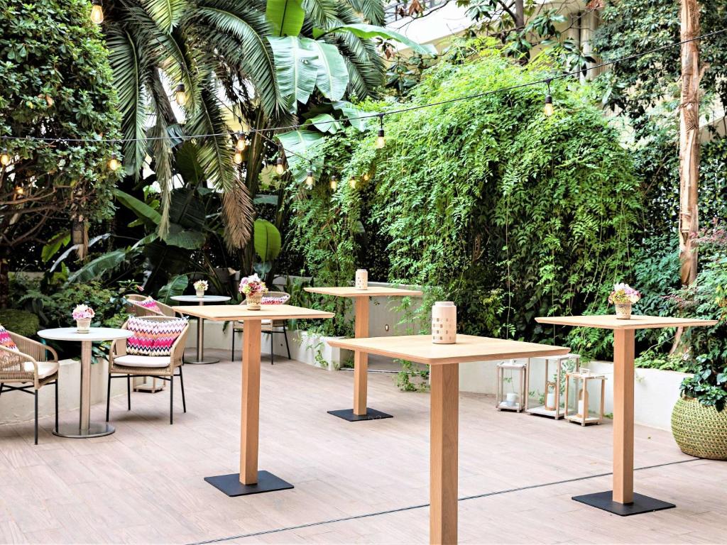 a group of tables and chairs in a garden at Croisette Beach Hotel Cannes - MGallery Collection in Cannes
