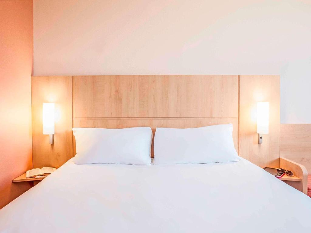 a large white bed with two pillows in a room at ibis London Elstree Borehamwood in Borehamwood