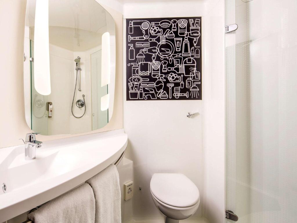 a bathroom with a sink and a toilet and a mirror at ibis London Elstree Borehamwood in Borehamwood