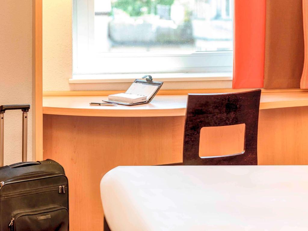 a laptop computer sitting on a desk next to a chair at ibis London Elstree Borehamwood in Borehamwood