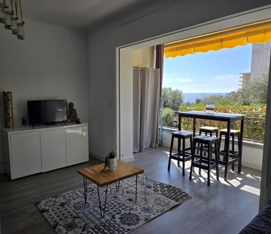 un salon avec une table et des chaises et un balcon dans l'établissement Escapade ensoleillée Cocon T1, à Ajaccio