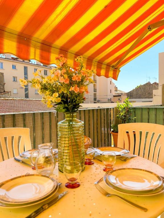 une table avec des assiettes et un vase avec des fleurs. dans l'établissement T2 sur le port de Sanary avec garage, à Sanary-sur-Mer