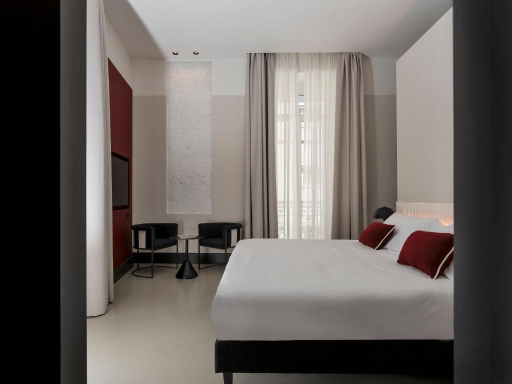 una camera da letto con un grande letto bianco con cuscini rossi di Adaram Suites a Napoli