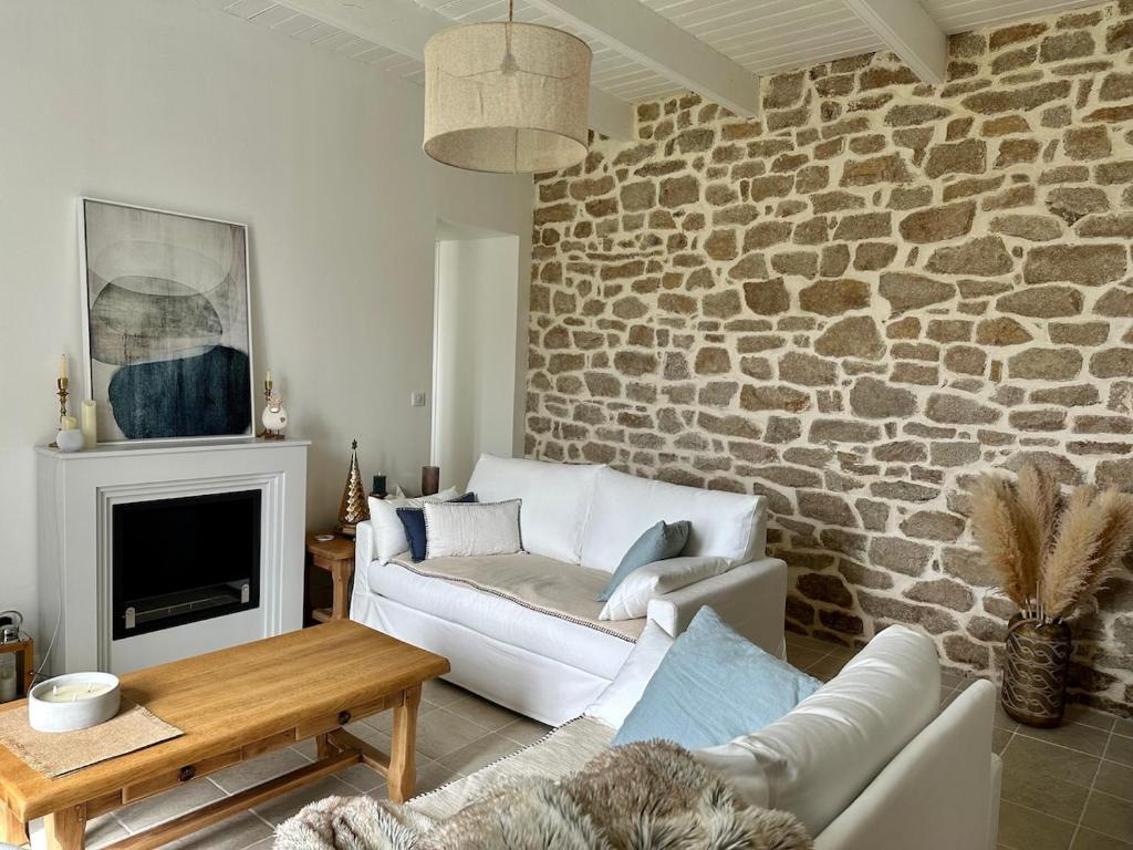 ein Wohnzimmer mit einer Couch und einer Steinwand in der Unterkunft Maison de charme 3 chambres plage de Lodonnec in Loctudy