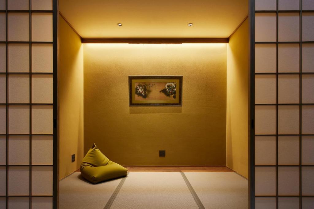 a room with a yellow pillow and a painting on a wall at Minn Nijo-jo in Kyoto