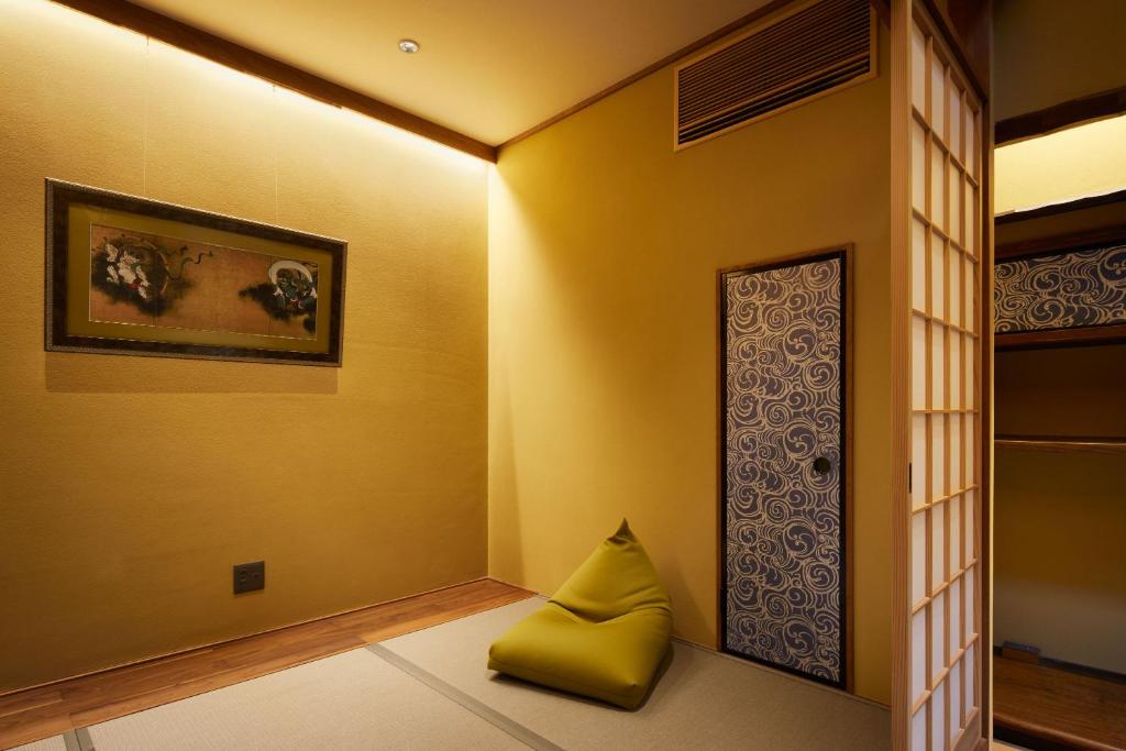 a room with a yellow wall with a yellow pillow next to a door at Minn Nijo-jo in Kyoto