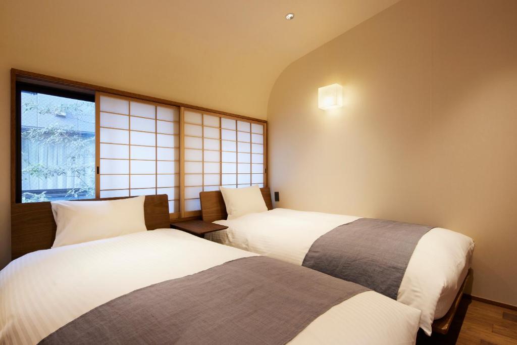 two beds in a room with two windows at Minn Nijo-jo in Kyoto
