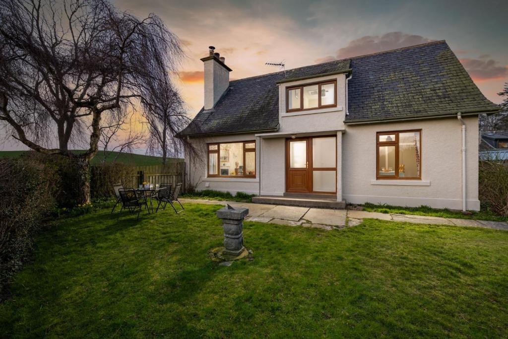 een wit huis met een brandkraan in de tuin bij Kirktoun Cottage in Duffus