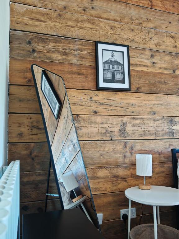 a room with a wooden wall with a chair and a table at Draycote House in Kings Lynn