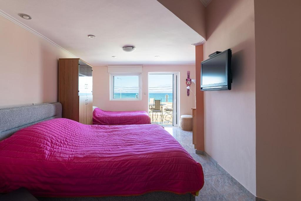 ein Schlafzimmer mit zwei Betten und einem Flachbildfernseher in der Unterkunft LIVAS Corinth Seaside Family Apartment in Kórinthos