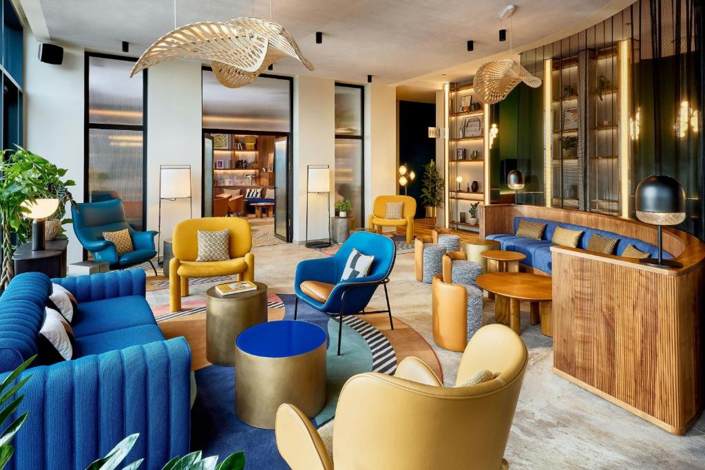 a lobby with blue and yellow chairs and tables at Courtyard by Marriott Lyon Eurexpo Stadium in Genas