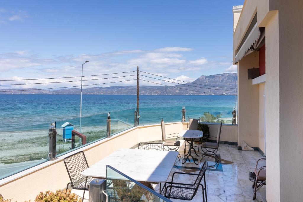 a balcony with a table and chairs and the ocean at LIVAS Corinth Seaside Family Apartment in Korinthos