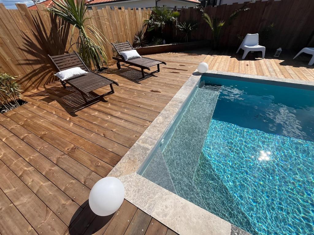 - une piscine avec deux chaises à côté d'une terrasse en bois dans l'établissement Villa Zerua & Spa, à Mimizan