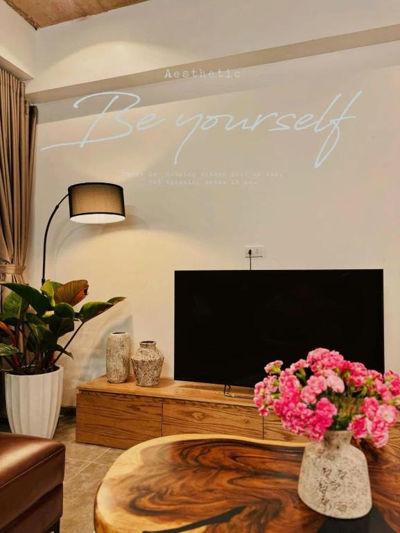 a living room with a tv and a table with flowers at Ngoc Anh Homestay's in Ha Long