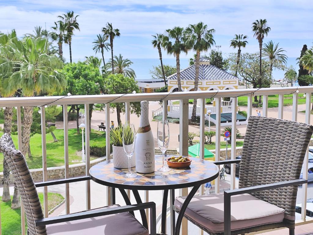 - une table avec une bouteille de vin et 2 chaises sur un balcon dans l'établissement Apartamento El Nido, à Torre del Mar