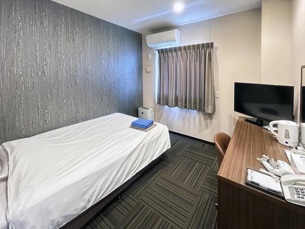 une chambre avec un lit, un bureau et une télévision dans l'établissement Business Hotel Goi Onsen - Vacation STAY 78219v, à Ichihara