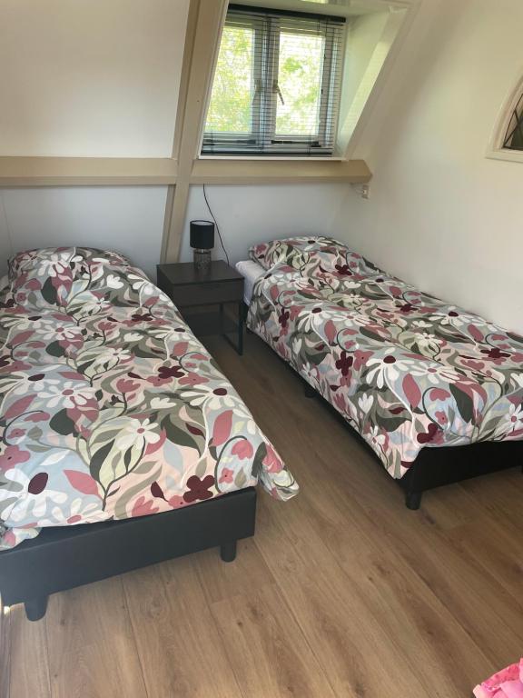 two beds sitting in a room with wooden floors at Holiday in Spakenburg t Afferhuus in Spakenburg