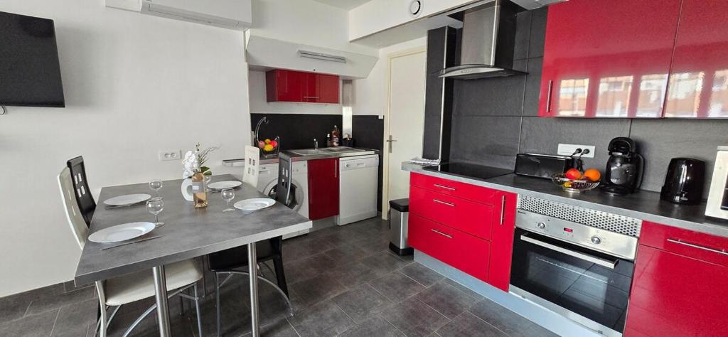 - une cuisine avec des placards rouges et une table dans l'établissement Nid de vacances à Valras - Clim et proche plage, à Valras-Plage
