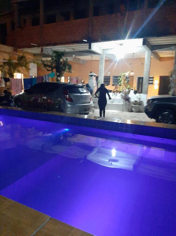 a person standing next to a swimming pool at night at Linda Pousada pra Final de Ano com Piscina a 5 Minutos da Praia in Peruíbe