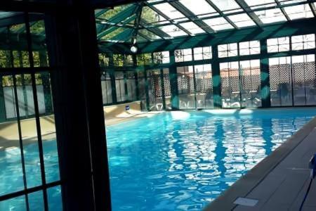 a large pool with blue water in a building at Studio dans une residence hoteliere avec piscine couverte in La Rochelle