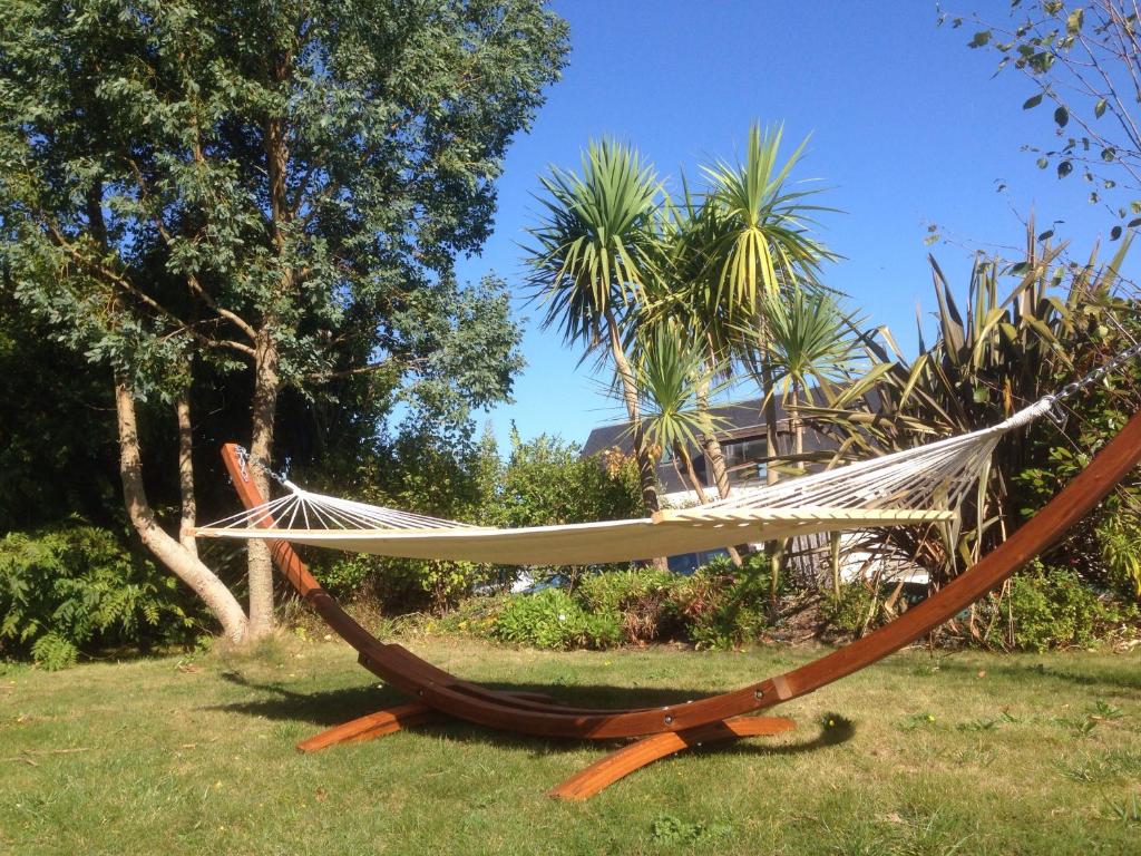 un hamac dans l'herbe avec une maison en arrière-plan dans l'établissement Séjour détente en famille à deux pas de la plage, à Saint-Pol-de-Léon
