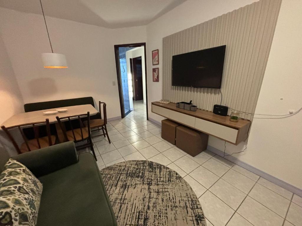 a living room with a couch and a television on a wall at Casa em Curitiba perto da Pedreira e Opera de Arame, com Ar Condicionado 3Quartos in Curitiba