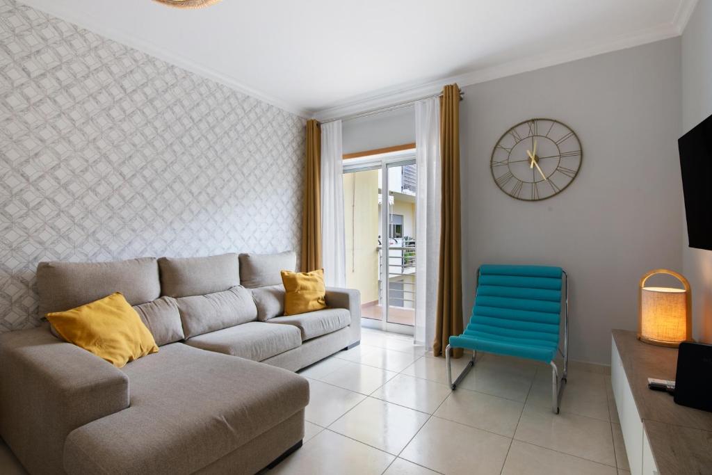 Una sala de estar con un sofá y una silla azul. en Apartamento T2 Rio E Mar, en Vila Real de Santo António