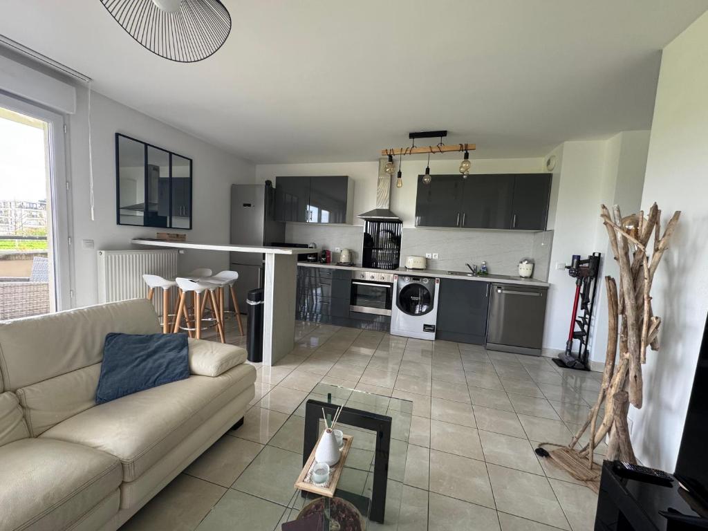 een woonkamer met een bank en een keuken bij Les jardins de Disney in Ferrières-en-Brie