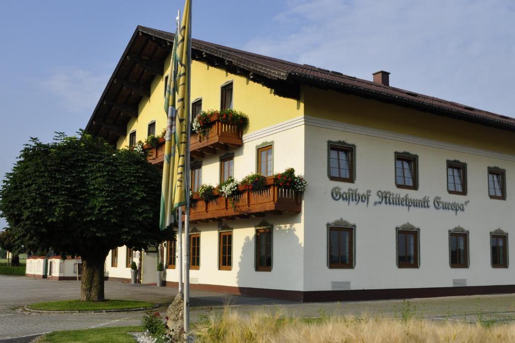 un edificio con una bandera delante de él en Hotel - Garni Mittelpunkt-Europa GmbH, en Braunau am Inn