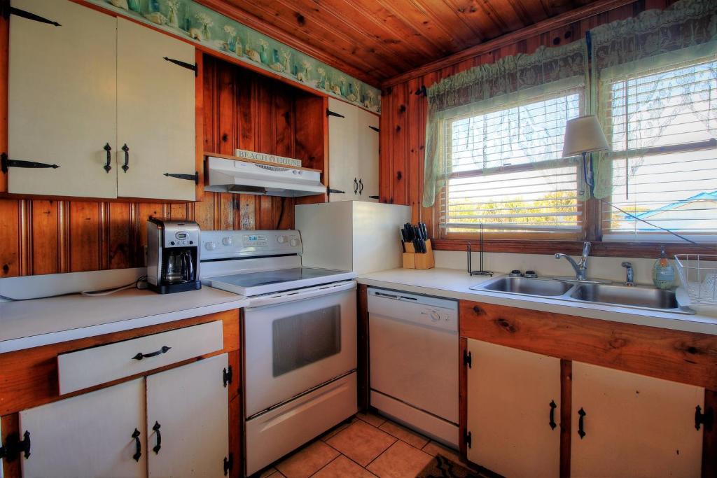 a kitchen with white appliances and wooden cabinets at Averette Cottage by Carolina Beach Realty in Carolina Beach