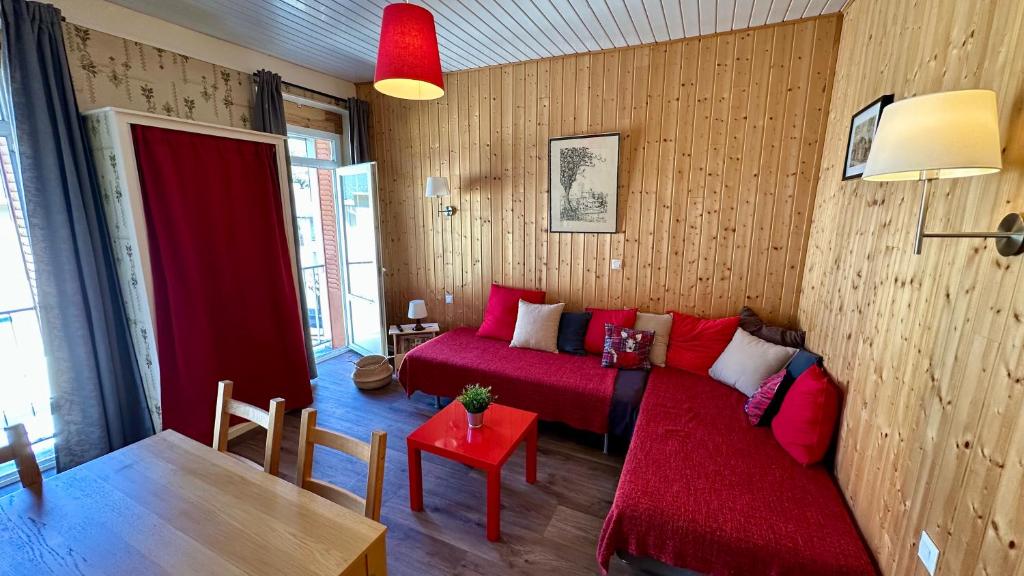 - un salon avec un lit rouge et une table dans l'établissement Le Pan de la Grange, Le Mont-Dore 5pers, à Le Mont-Dore