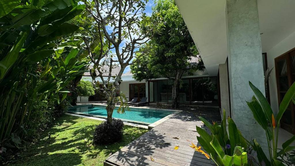 a swimming pool in a yard next to a house at Villa TELU in Canggu