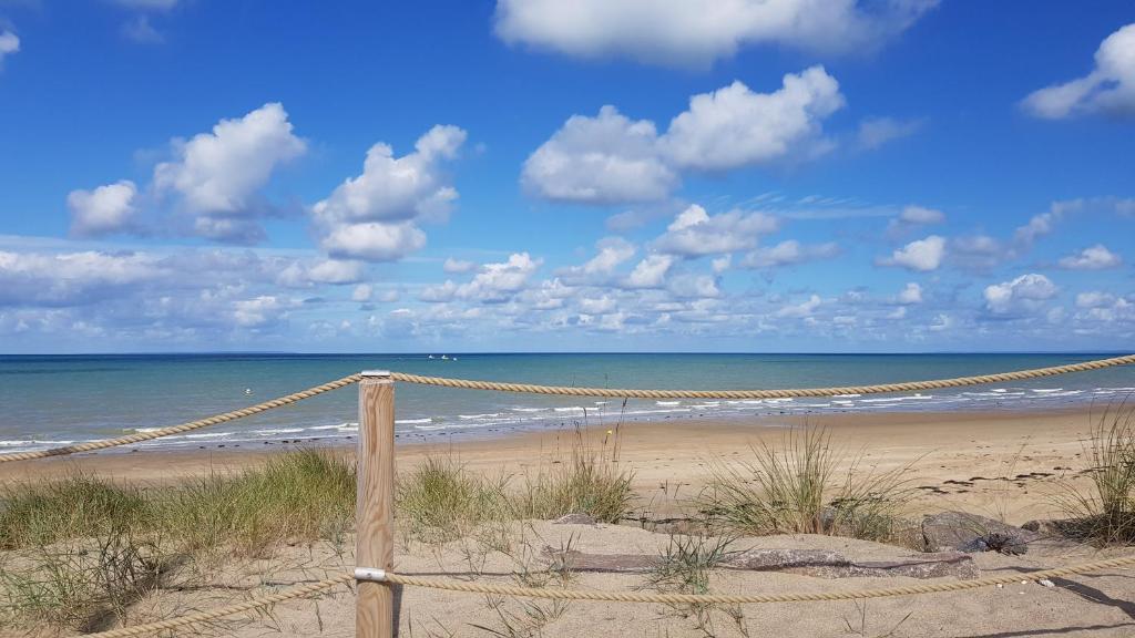 une plage avec un hamac sur le sable et l'océan dans l'établissement Esprit Mer, à Gouville-sur-Mer