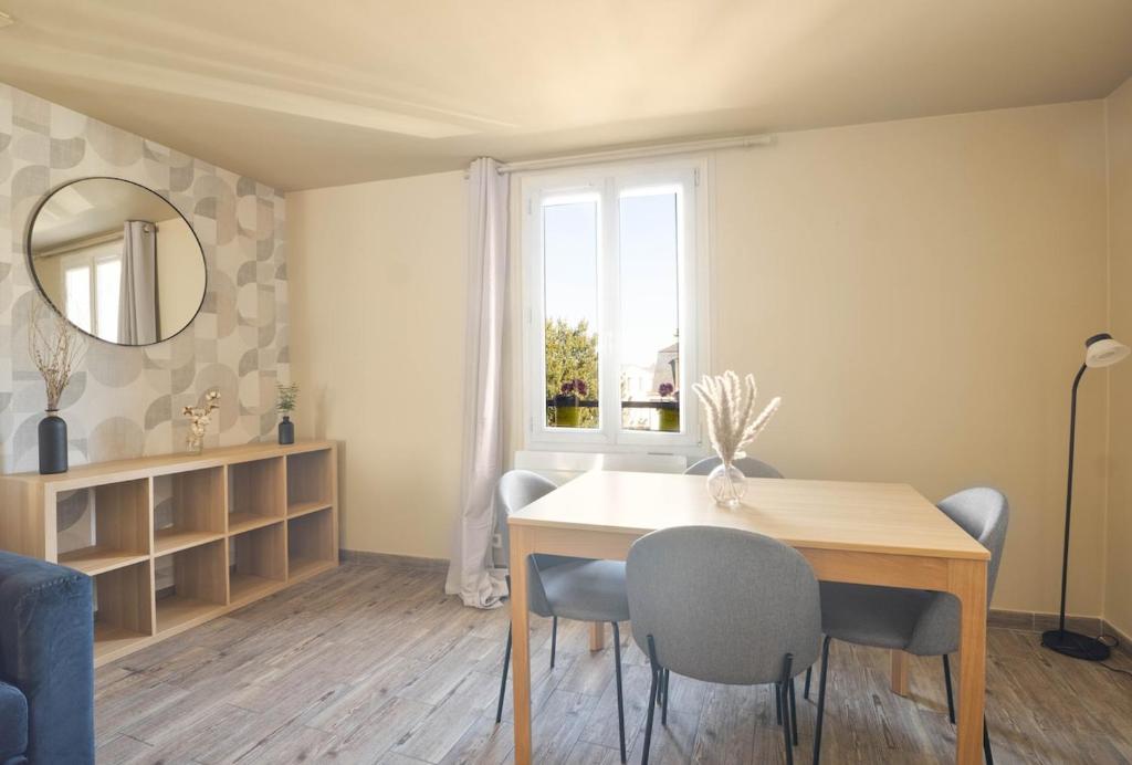 une salle à manger avec une table et des chaises et une fenêtre dans l'établissement Appartement tout confort entre Versailles & Paris - Calme et 2 chambres équipées, à Le Port-Marly