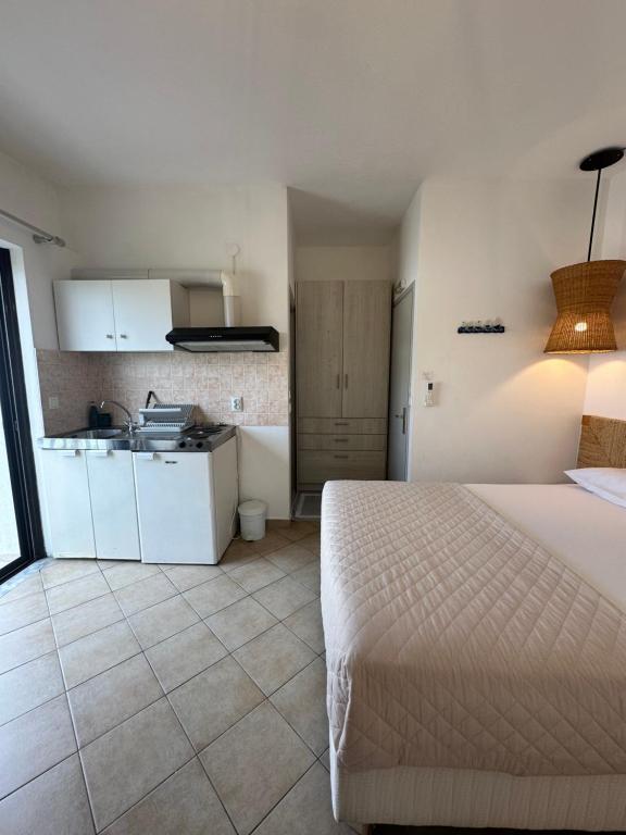 a bedroom with a white bed and a kitchen at Tsimiklis Apartments in Finikounta