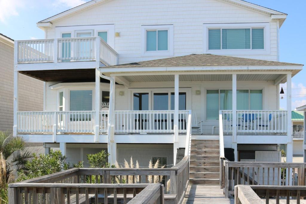 a white house with a deck and stairs at Casablanca by Carolina Beach Realty in Kure Beach