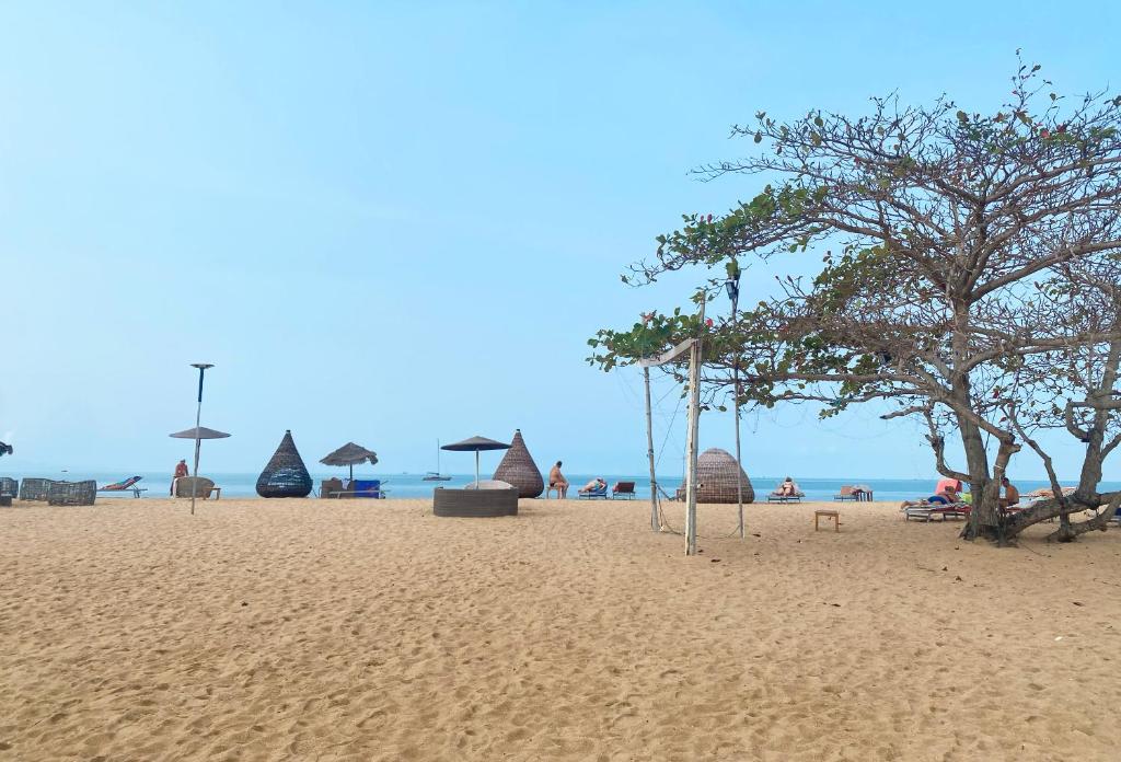 Una playa de arena con sombrillas y gente en la playa. en Charming Beachfront Retreat, Minutes from Pattaya, en Na Jomtien