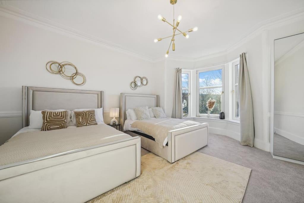 Un dormitorio blanco con dos camas y una ventana. en Large Terraced Home with Parking, en Glasgow
