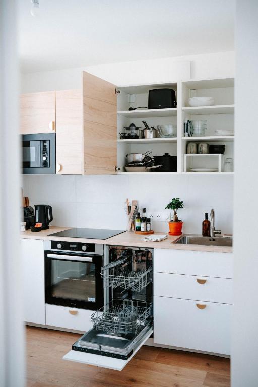 La cuisine est équipée de placards blancs et d'un lave-vaisselle. dans l'établissement T1bis cocooning au calme, à Brest